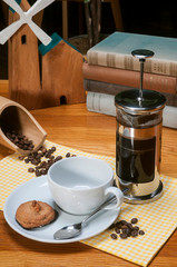French press coffee maker with empty cup and coffee beans