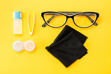 Accessories for storing lenses: a bottle of liquid,  container and tweezers, glasses and cloth on a...