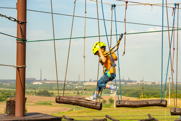 The boy goes on logs on the cable car in an extreme park.