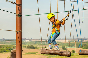 A boy in a yellow helmet overcomes an obstacle on the cable car in an extreme park.