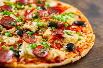 Pizza with Chicken meat, Mozzarella cheese, pepperoni, tomato, olive, salami. Italian pizza on wooden background