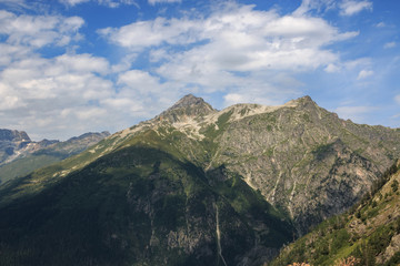 Naklejka premium Closeup view mountains scenes in national park Dombai, Caucasus, Russia, Europe. Summer landscape, sunshine weather, dramatic blue sky and sunny day