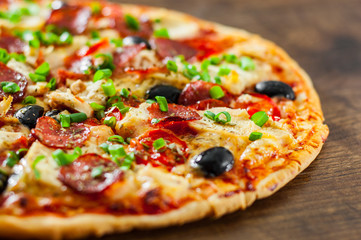 Pizza with Chicken meat, Mozzarella cheese, pepperoni, tomato, olive, salami. Italian pizza on wooden background