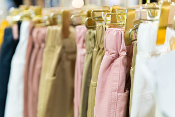 Hanger gold clothes with many pastel trousers.