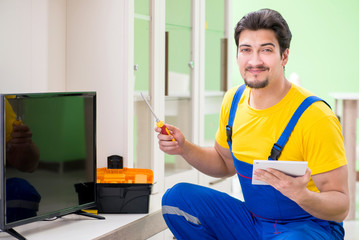 Male professional serviceman repairing tv at home