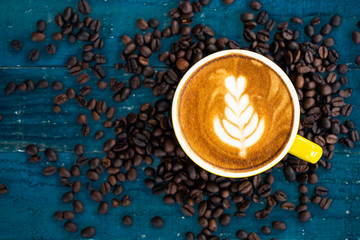 Coffee latte with coffee beans on blue grunge wooden background