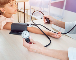 Doctor measuring blood pressure of a little girl.