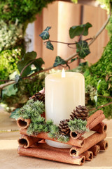 Christmas candle holder with cinnamon sticks, moss and anise stars.