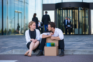 Fired businessman sitting on street