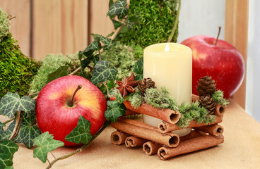Christmas candle holder with cinnamon sticks, moss and anise stars.