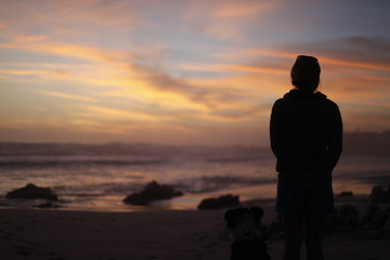 dog and woman on the beach at sunset