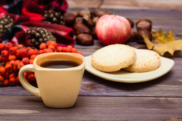 Autumn still life - coffee, cookies, a plaid, a notebook and a pencil on a wooden background