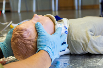 Human hands stabilisations the neck from a medical training puppet for ambulance man