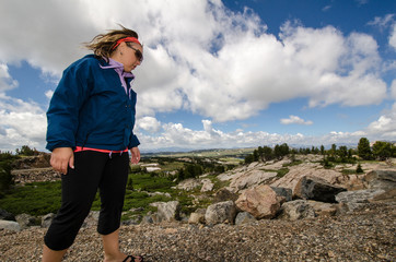 Cautious blonde woman watches her footing as she explores rocks along the Beartooth Highway in Montana