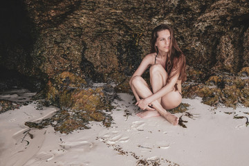 Attractive young woman on the background of a coral reef on the white sand Toned photo