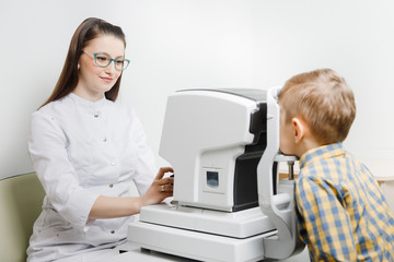 Ophthalmologist woman doctor examining vision of little child in clinic