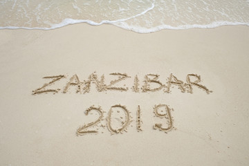 Fototapeta premium Zanzibar napis na jasnym piasku i falach oceanicznych