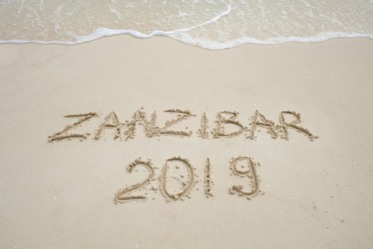 zanzibar script on light sand and ocean wave