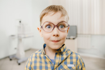 smiling child boy in glasses checks eye vision pediatric ophthalmologist.