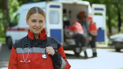 Paramedic posing for camera, ambulance crew transporting patient to clinic