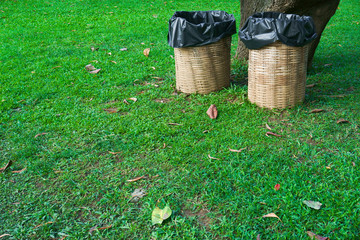 Fototapeta premium Trash bin made of bamboo baskets on green grass at public park