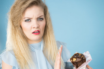 Skeptical woman holding chocolate cupcake muffin