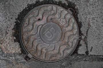 Manhole cover in the road of asphalt