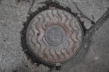 Manhole cover in the road of asphalt
