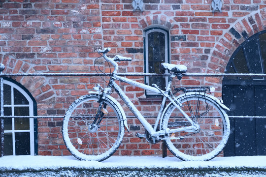 Winter day in city. Snow covered bicycle parked on streen