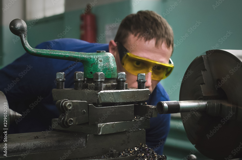 Wall mural turner worker is working on a lathe machine in a factory.