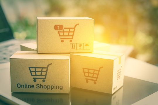 Online shopping and ecommerce over internet concept : Boxes with shopping cart logo on smart tablet and laptop computer, depicts consumers always buy goods or things directly from online retail store.