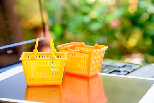 Global or worldwide online shopping / retail ecommerce and delivery service concept : Grocery baskets on a laptop, depicts consumers purchase or order products from online suppliers or digital stores.
