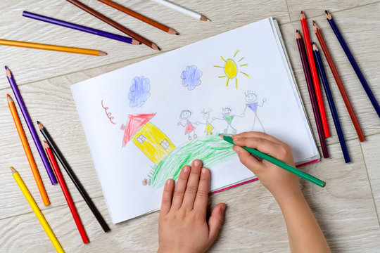 The child draws his family on a piece of paper with colored pencils. What can a children's picture tell. The concept of child psychology.