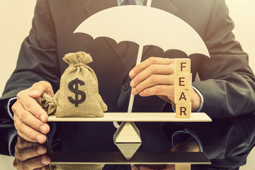 Fear and greed or anxiety in financial market concept : Businessman carries a white umbrella,...