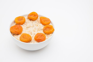 Oatmeal with dried apricots in white bowl on white bakcground. Isolated on white. Healthy food