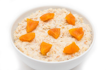 Oatmeal with dried apricots in white bowl on white bakcground. Isolated on white. Healthy food