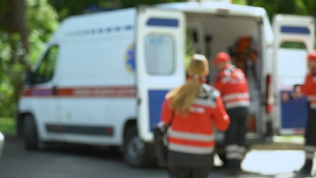 Paramedic looks at camera, getting into ambulance, patient's transportation