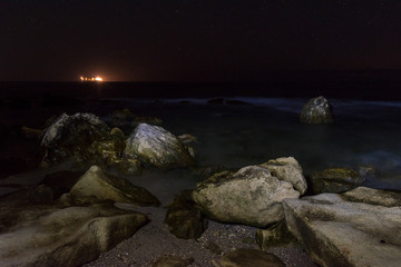 Summer night on the beach. Light is reflected in the water.