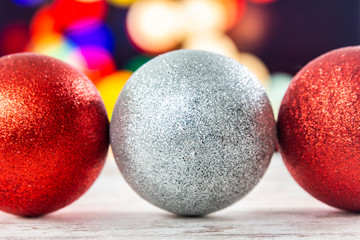 Three Christmas balls with a Christmas lighs background