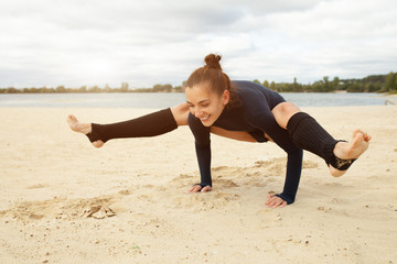 Fototapeta na wymiar Beautiful middle-aged girl doing yoga exercises on the shore of a beautiful lake on a sunny autumn day