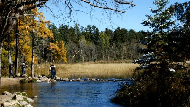 Lake Itasca held behind a man made dam at the headwaters of the Mississippi River at Lake Itasca State Park in Minnesota. Tourists take pictures by the rocks.