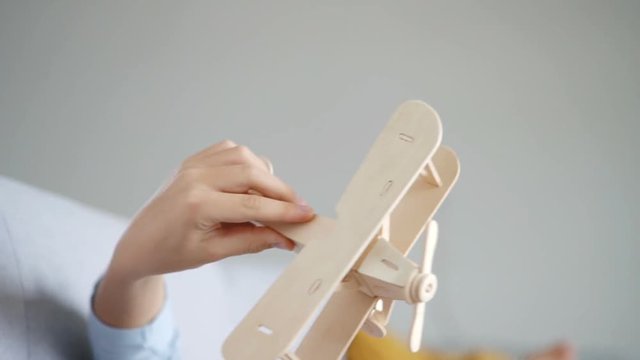Slow motion footage of the boy`s hand playing with wooden plane toy model