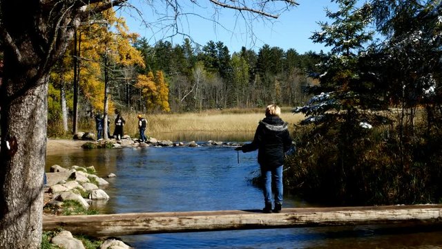 Lake Itasca held behind a man made dam at the headwaters of the Mississippi River at Lake Itasca State Park in Minnesota. Tourists take pictures by the rocks.