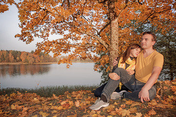 Young couple on lake coast. Sunny Autumn Day