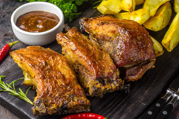 Barbecued pork ribs seasoned with a spicy bbq sauce served with fries on an old rustic wooden chopping board in a country kitchen