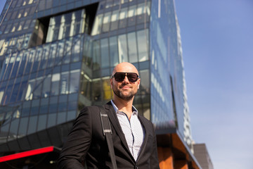 Fototapeta premium Handsome elegant businessman with sunglasses in front of office building