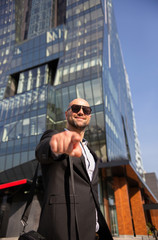 Handsome elegant businessman with sunglasses in front of office building