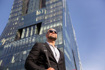 Handsome elegant businessman with sunglasses in front of office building