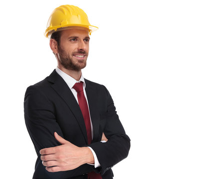 confident businessman wearing a yellow helmet looks up to side