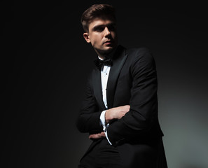 confident groom with hands folded looks to side